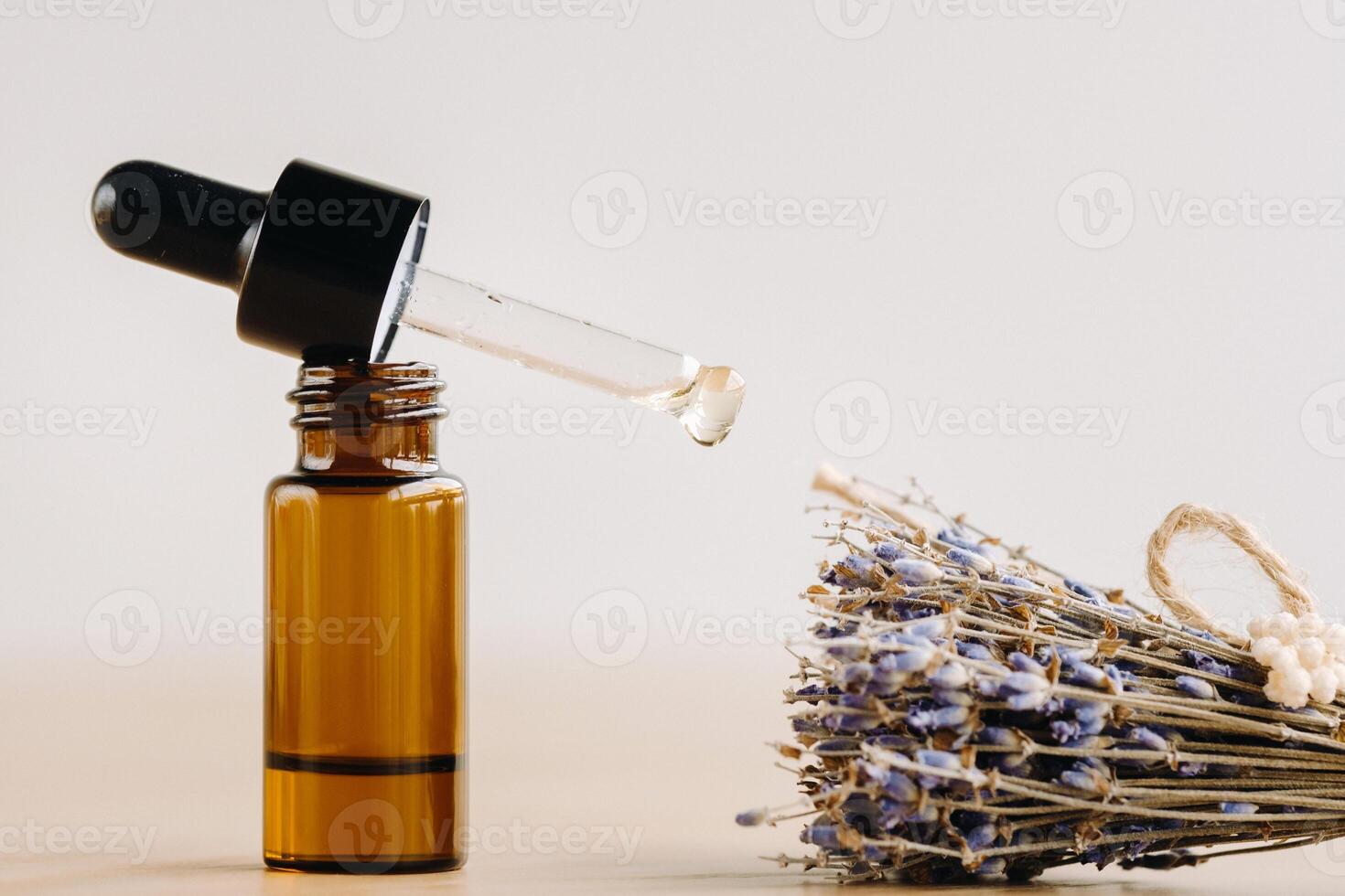 Essential oil in one bottle and dried lavender standing on the surface photo
