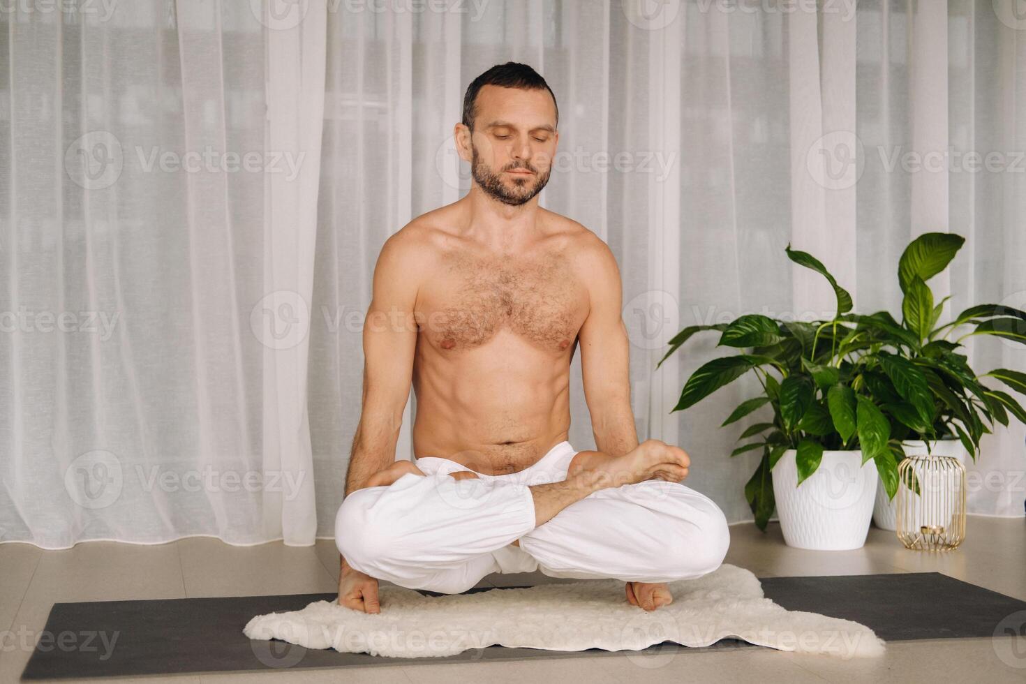 a man with a bare torso does yoga in a fitness room. the concept of a healthy lifestyle photo