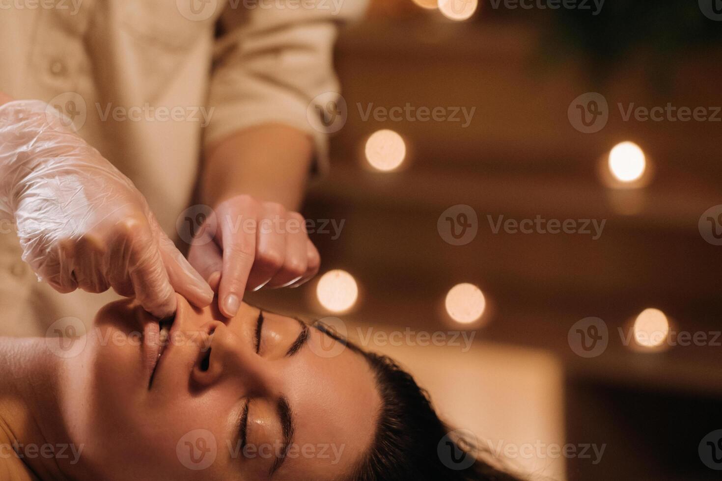A cosmetologist girl does a facial and neck massage to a girl in the office for skin elasticity photo