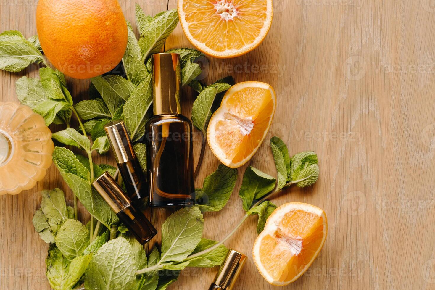 Essential oil in bottles with the aroma of orange and mint lying on a wooden surface photo