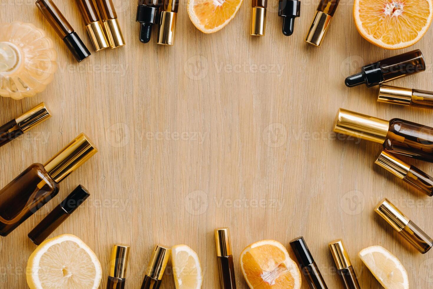 Essential oil in bottles and lemons, oranges lying on a wooden surface photo