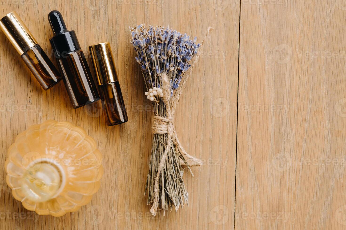 Essential oil in one bottle and dried lavender standing on the surface photo