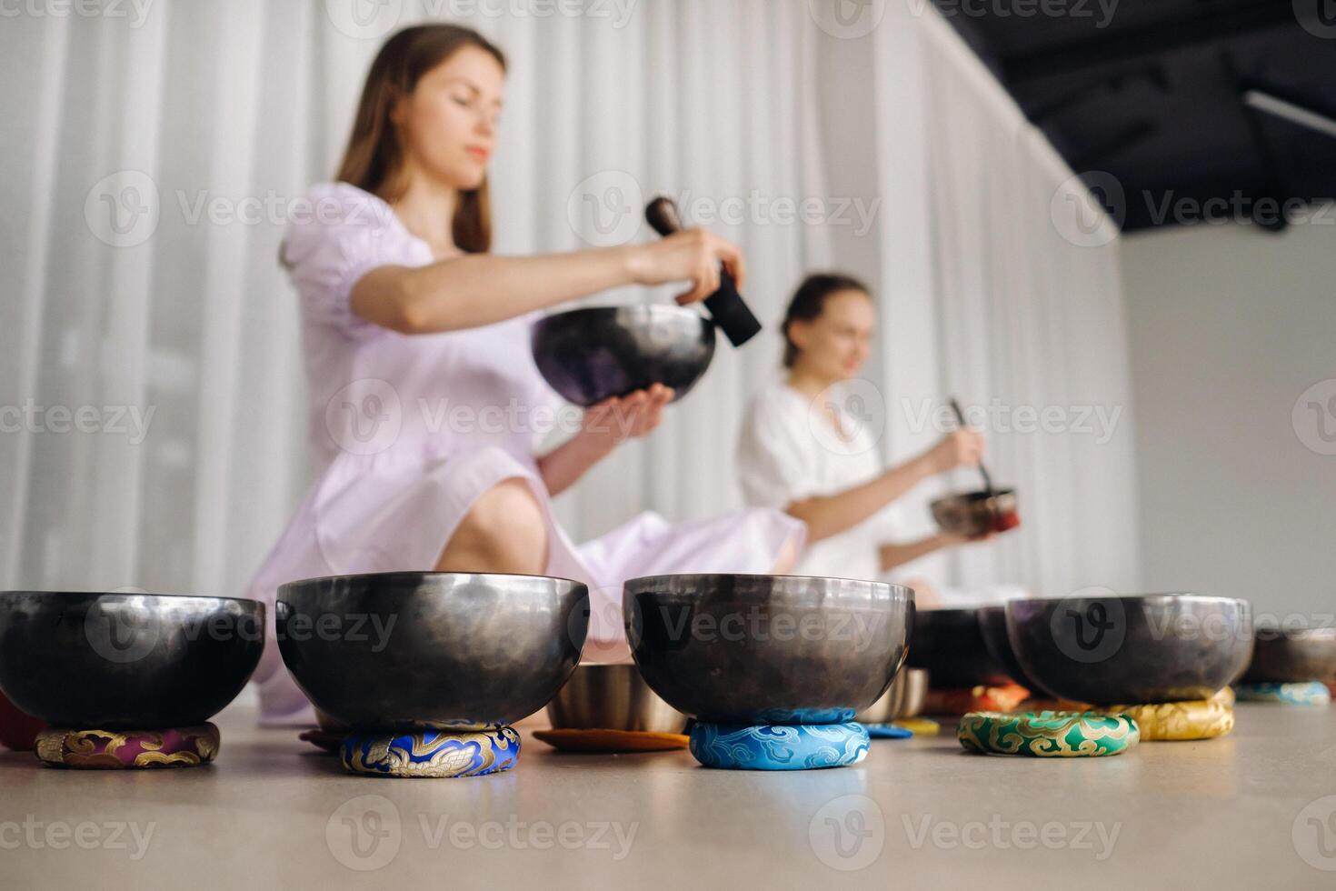 Two female yoga teachers play on Tibetan bowls in the gym during a yoga retreat photo