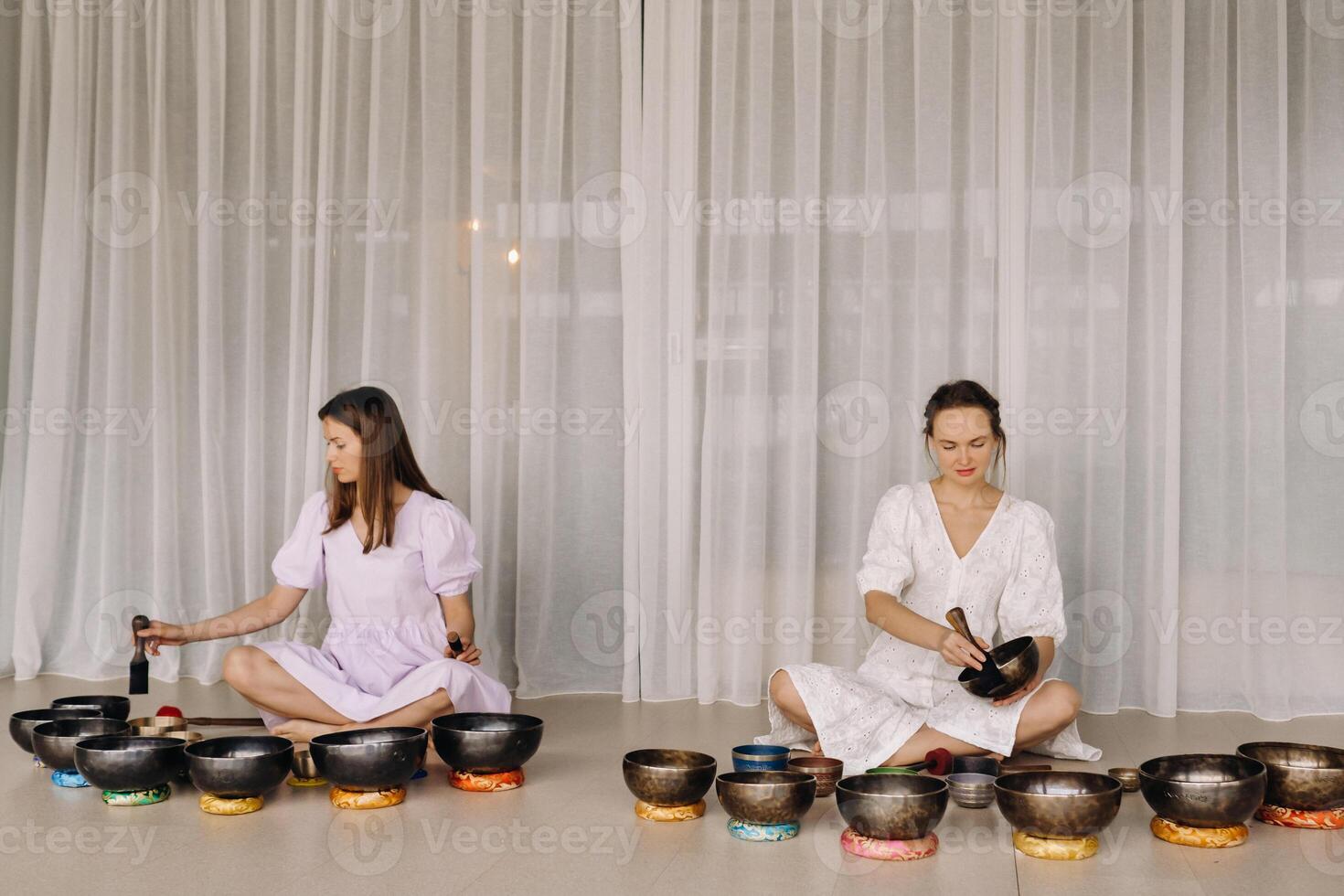 Two female yoga teachers play on Tibetan bowls in the gym during a yoga retreat photo