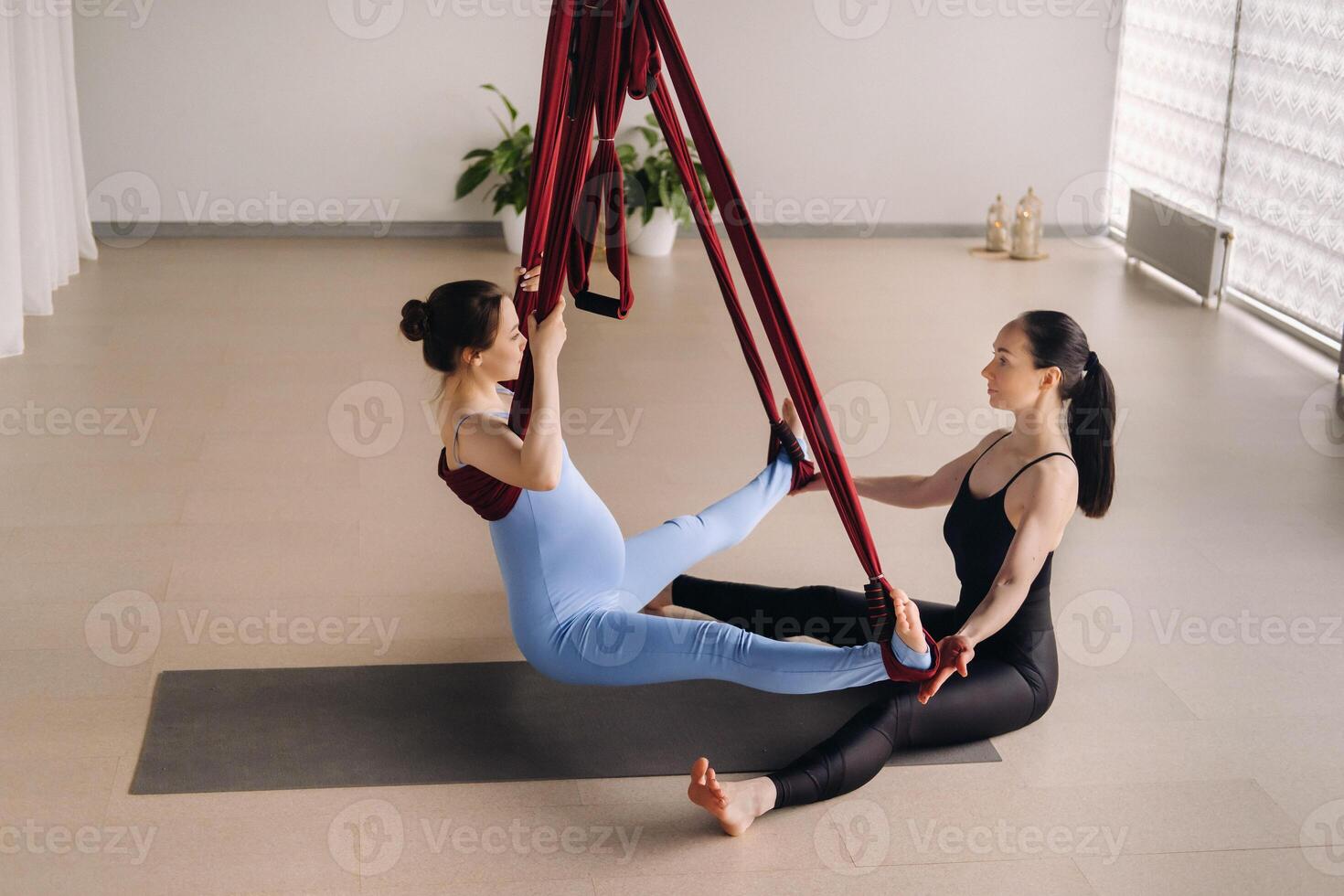 embarazada muchacha. un mujer con un entrenador lo hace yoga en un hamaca en el gimnasia. el concepto de un sano estilo de vida, maternidad foto