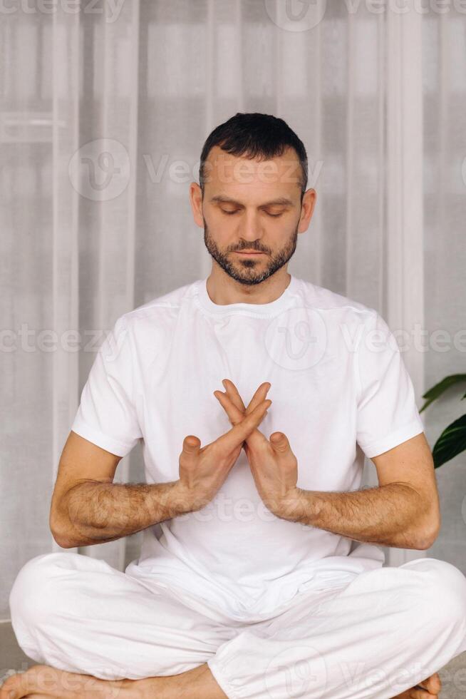 un hombre en blanco ropa de deporte es haciendo yoga con un aptitud habitación. el concepto de un sano estilo de vida foto