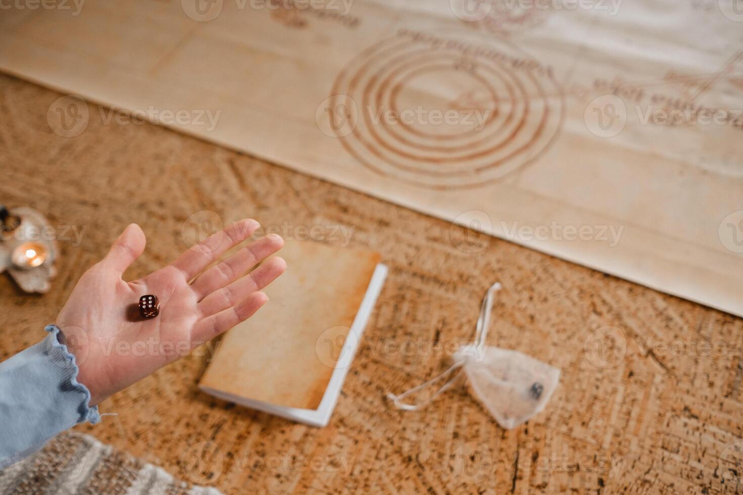 There is a dice in a person's hand. Close-up of a hand with a dice on the background of a notebook photo