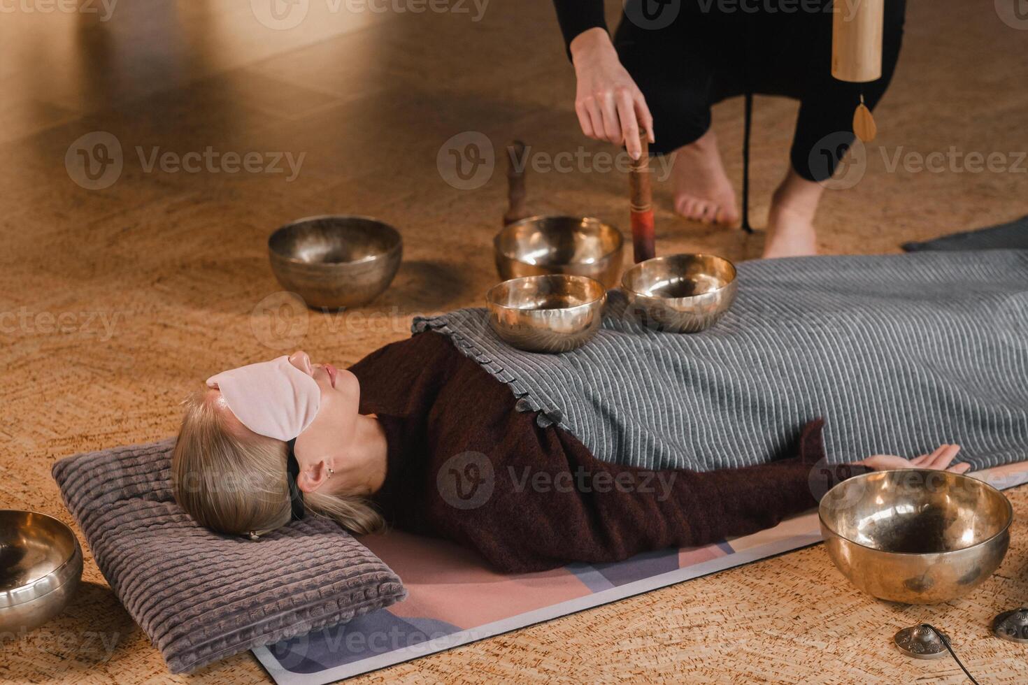 A young beautiful woman is doing a massage with singing bowls and a koshi bell to another girl. Sound therapy photo