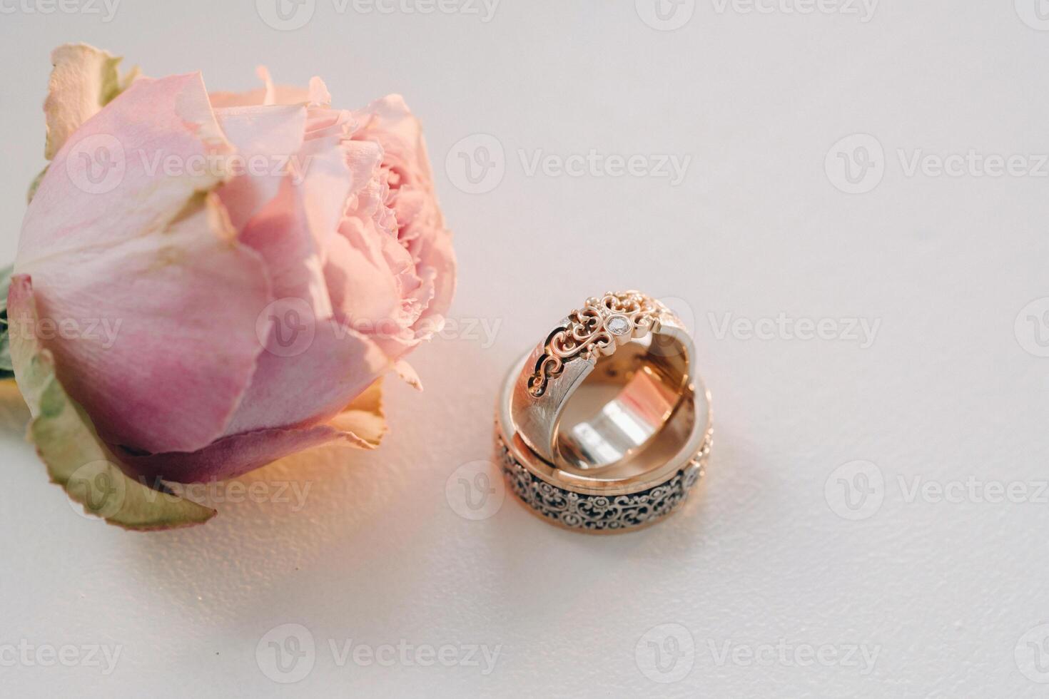 Designer wedding rings lying on the surface with a rose. Two wedding rings photo