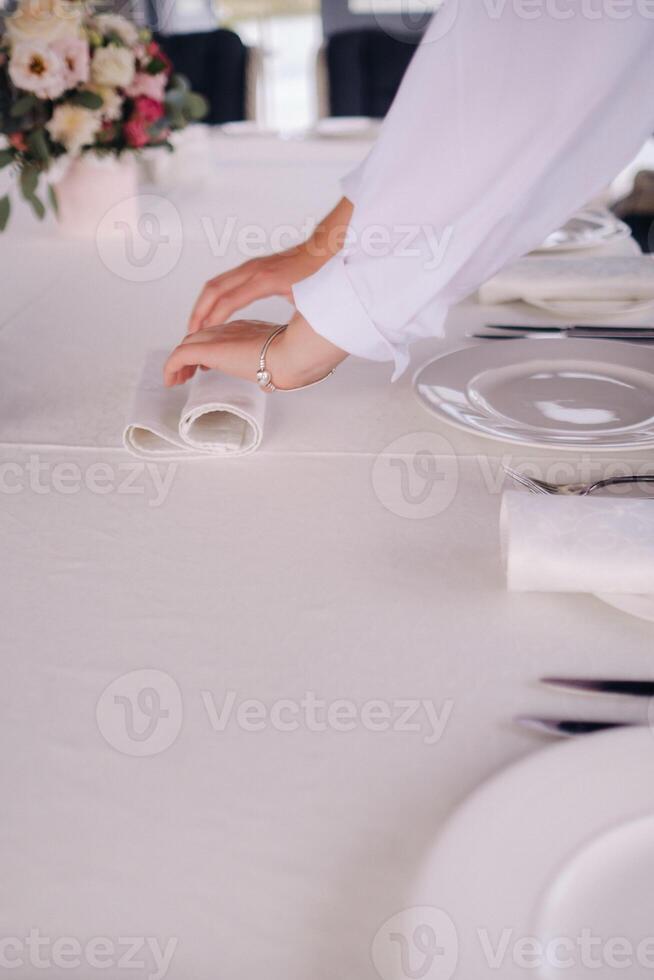 The waiter puts a white napkin on the plate. Beautiful table setting for a holiday without food photo