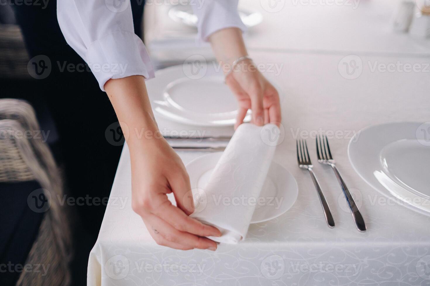 The waiter puts a white napkin on the plate. Beautiful table setting for a holiday without food photo