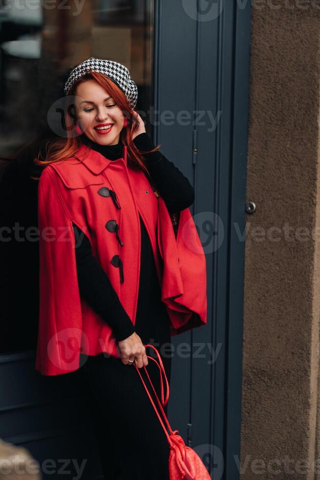 A beautiful stylish woman dressed in an elegant red coat with a stylish red handbag in the autumn city photo