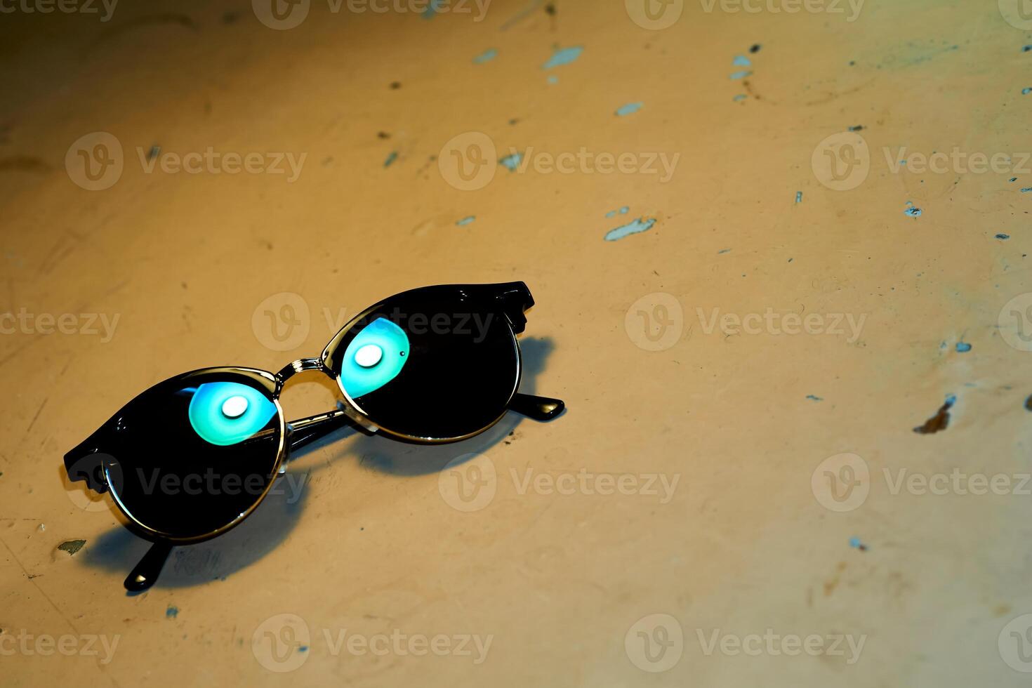 Sunglasses black with reflection of azure lamp on old shabby table photo