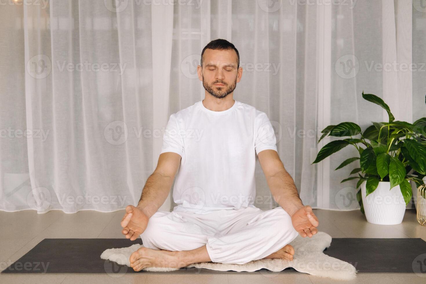 a man in white sportswear is doing yoga with a fitness room. the concept of a healthy lifestyle photo
