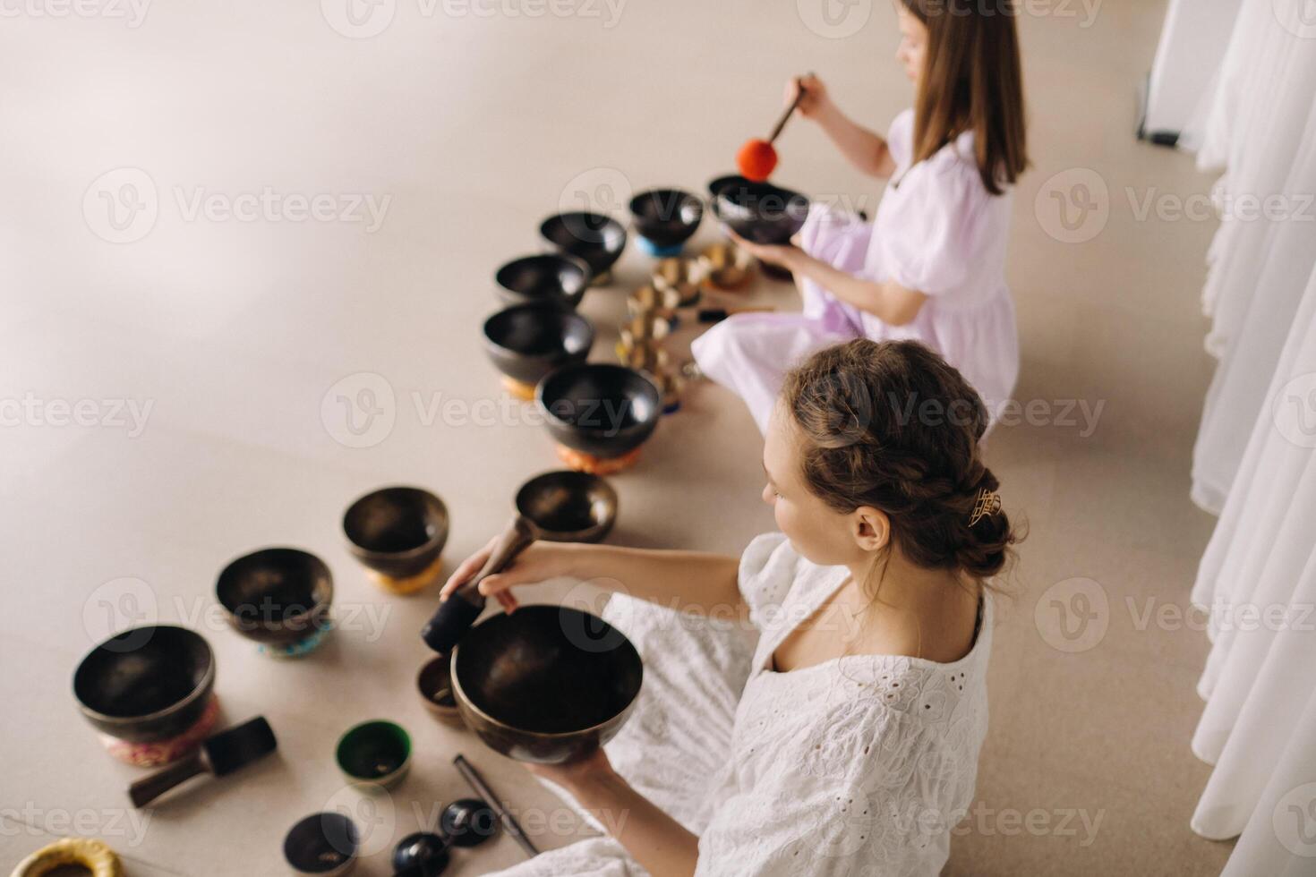 Two female yoga teachers play on Tibetan bowls in the gym during a yoga retreat photo