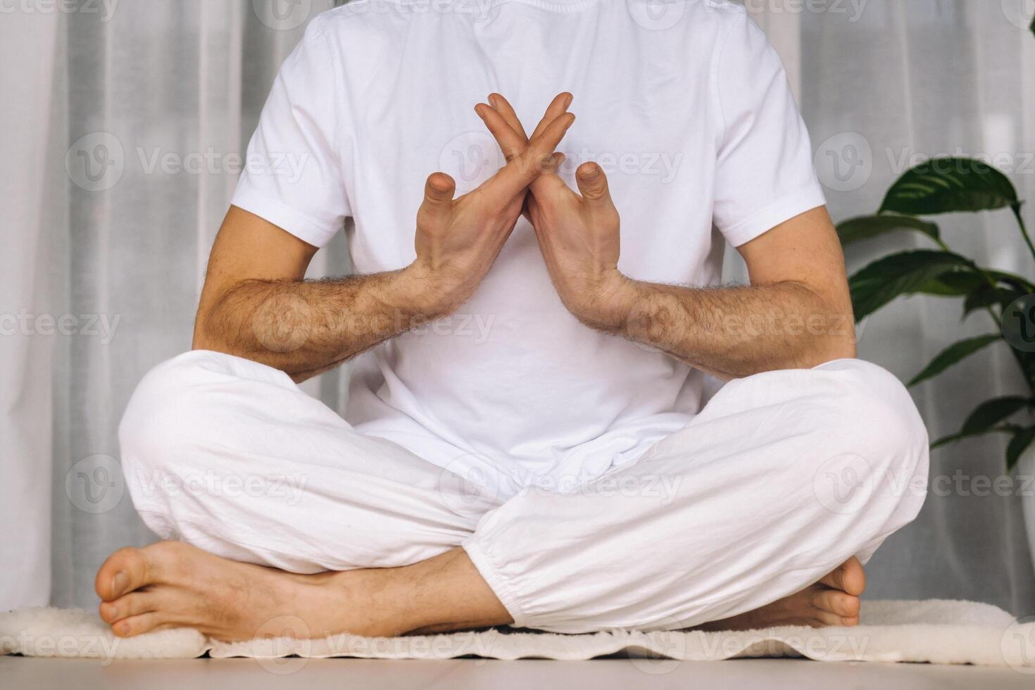 a man in white sportswear is doing yoga with a fitness room. the concept of a healthy lifestyle photo