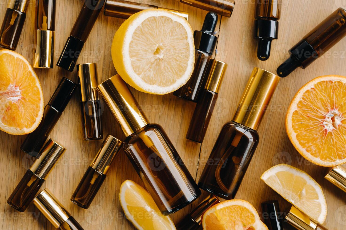 Essential oil in bottles and lemons, oranges lying on a wooden surface photo