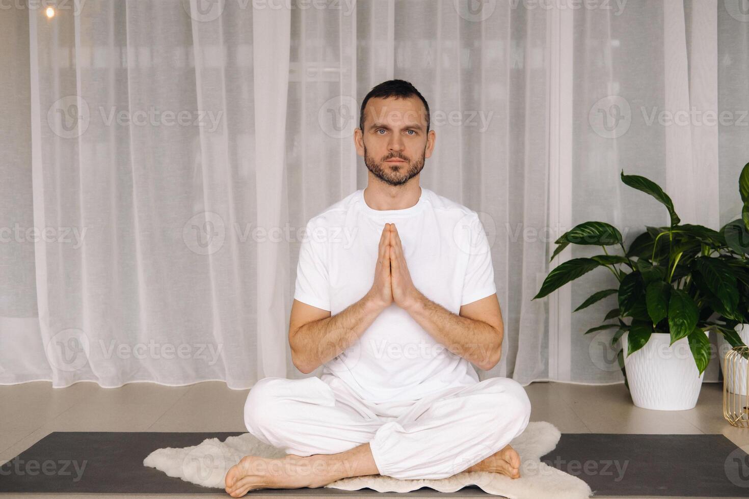 un hombre en blanco ropa de deporte es haciendo yoga con un aptitud habitación. el concepto de un sano estilo de vida foto