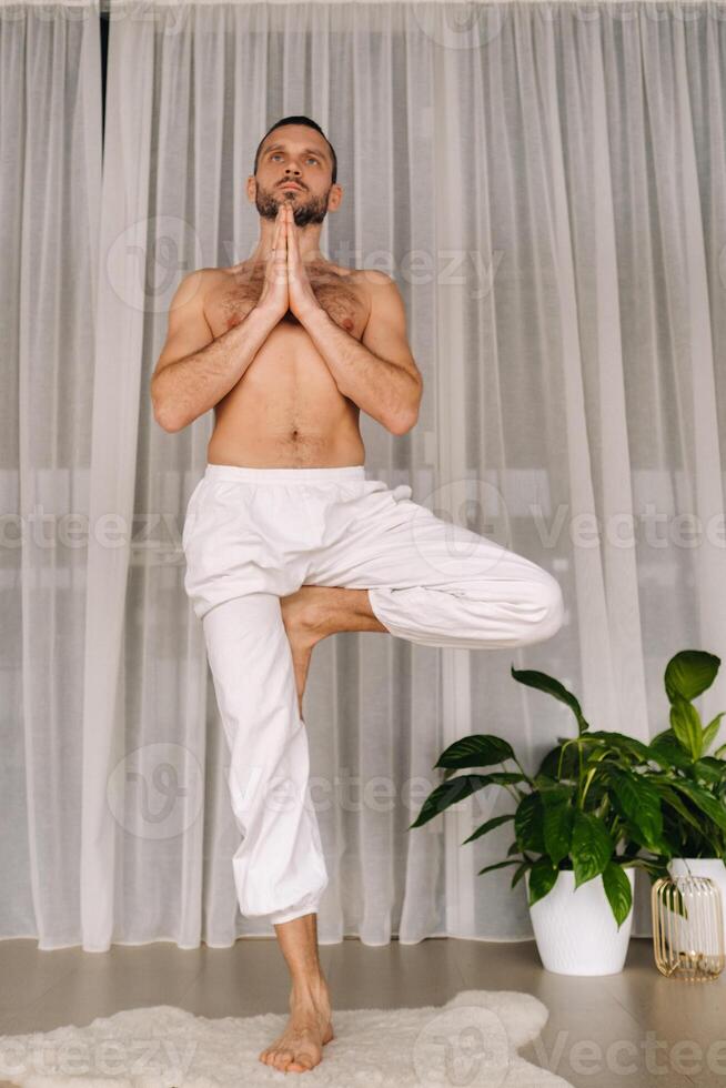 a man with a bare torso does yoga in a fitness room. the concept of a healthy lifestyle photo