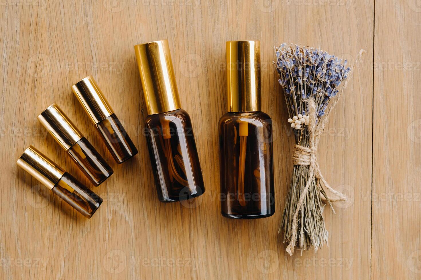 Essential oil in one bottle and dried lavender standing on the surface photo