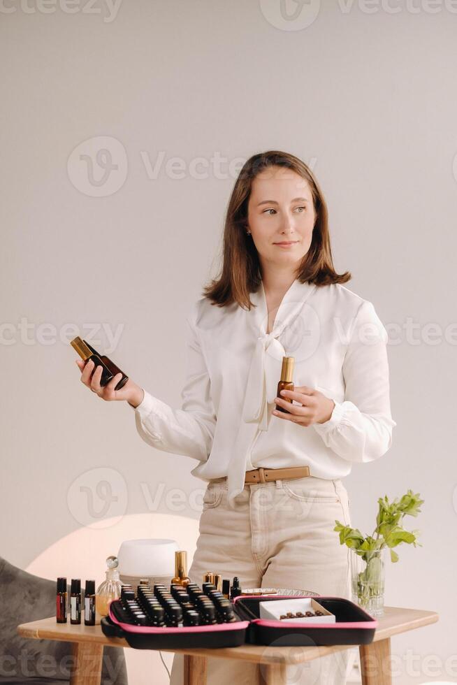 A girl with a white blouse holds bottles of essential oils in her hands photo