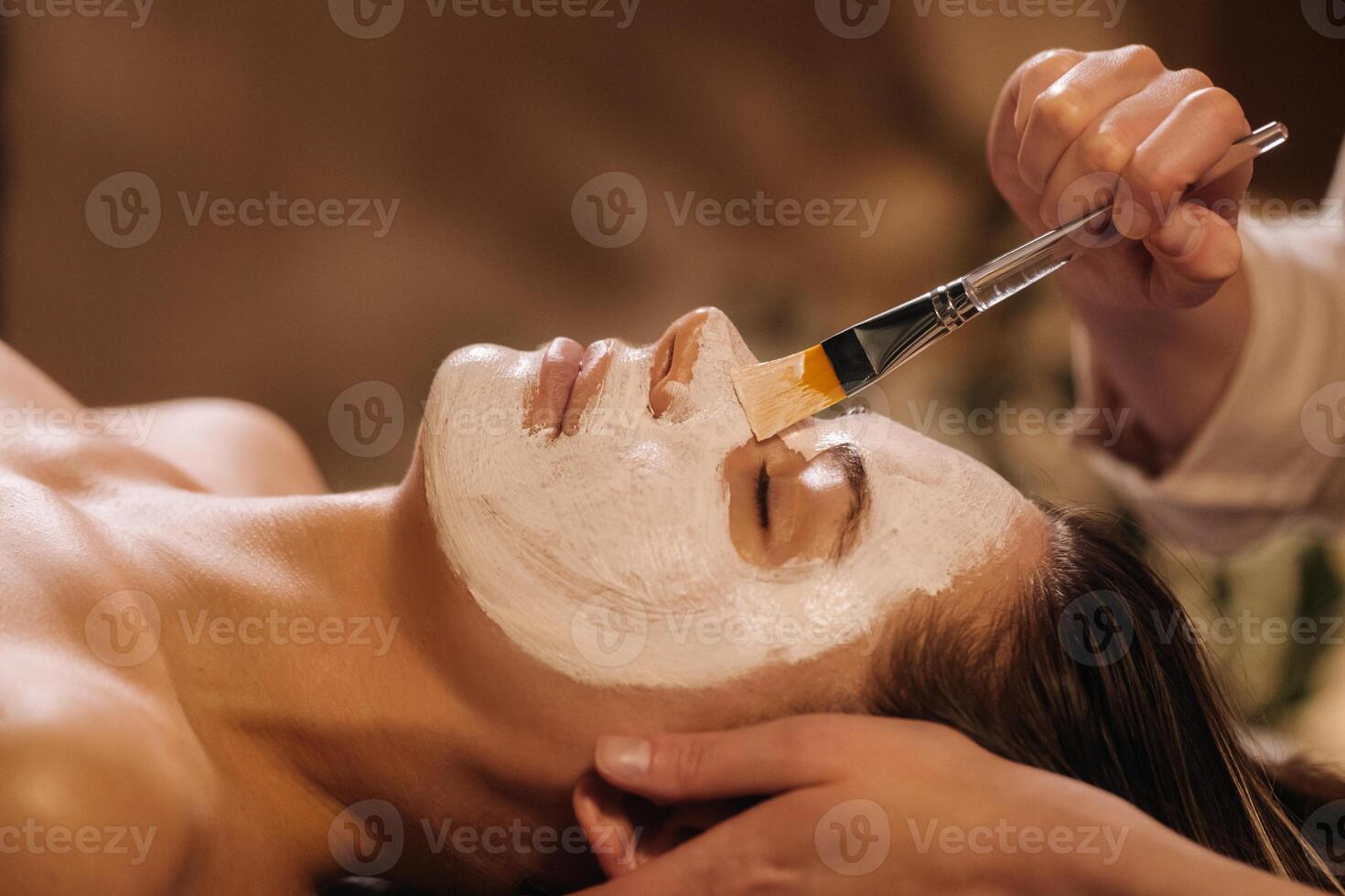 A cosmetologist makes a mask for a woman's face to rejuvenate the skin. Cosmetology photo