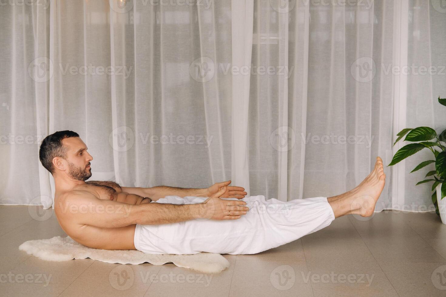 a man with a bare torso does yoga in a fitness room. the concept of a healthy lifestyle photo