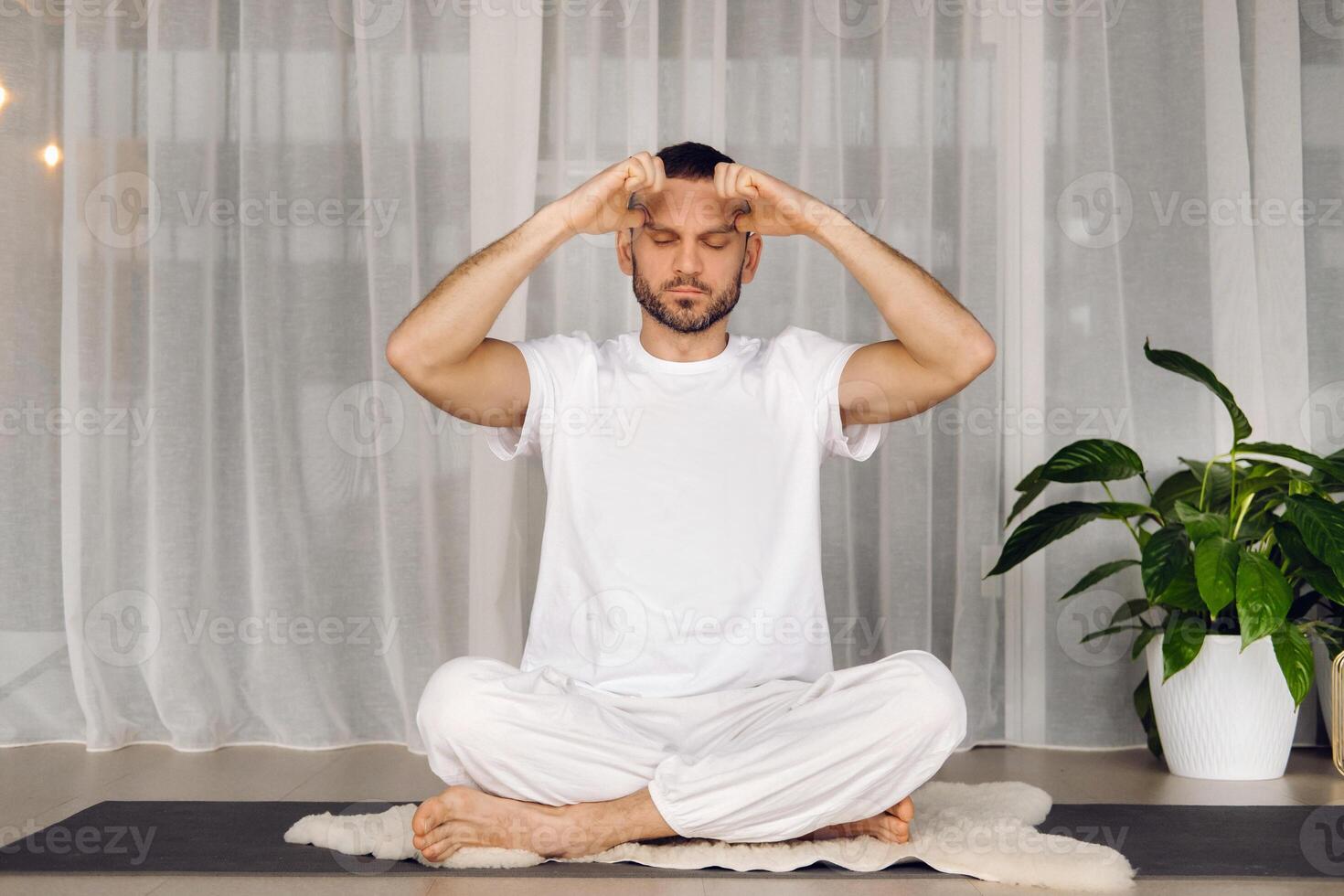 a man in white sportswear is doing yoga with a fitness room. the concept of a healthy lifestyle photo