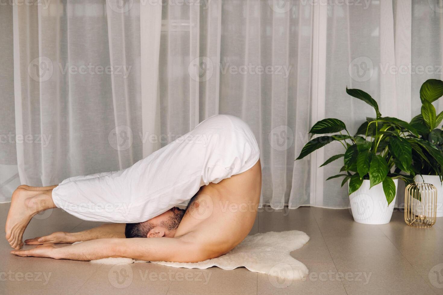 a man with a bare torso does yoga in a fitness room. the concept of a healthy lifestyle photo