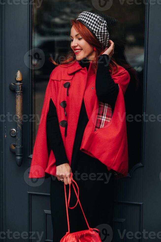 A beautiful stylish woman dressed in an elegant red coat with a stylish red handbag in the autumn city photo
