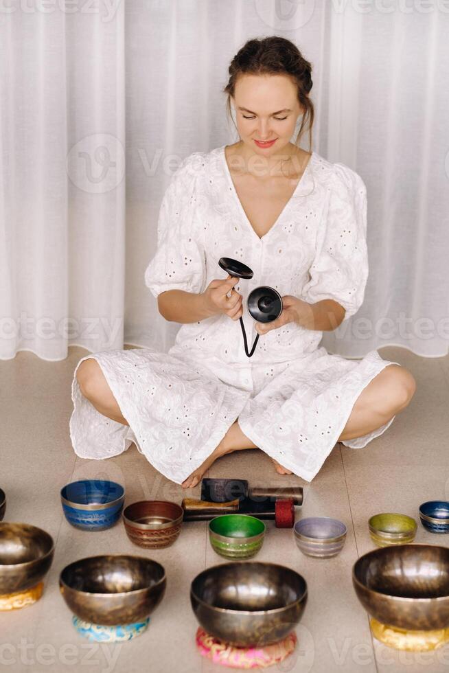 Portrait of a female yoga teacher playing a Tibetan bowl or singing a bell in the gym during a yoga retreat photo
