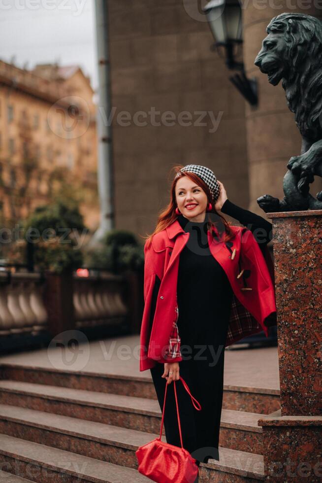 un hermosa elegante mujer vestido en un elegante rojo Saco con un elegante rojo bolso en el otoño ciudad foto