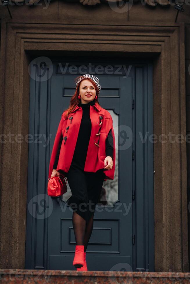 A beautiful stylish woman dressed in an elegant red coat with a stylish red handbag in the autumn city photo