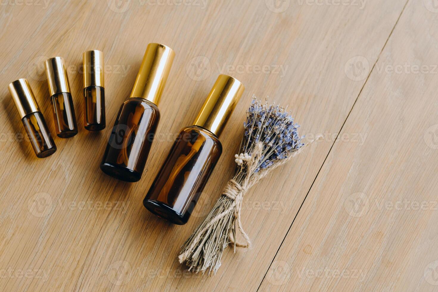 Essential oil in one bottle and dried lavender standing on the surface photo