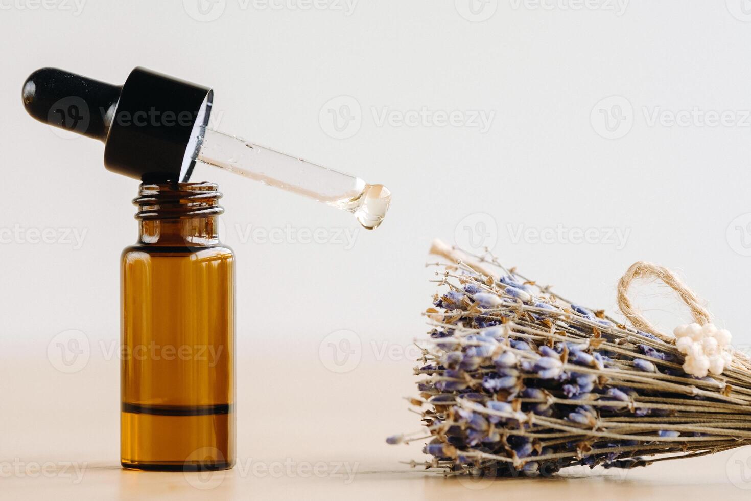 Essential oil in one bottle and dried lavender standing on the surface photo
