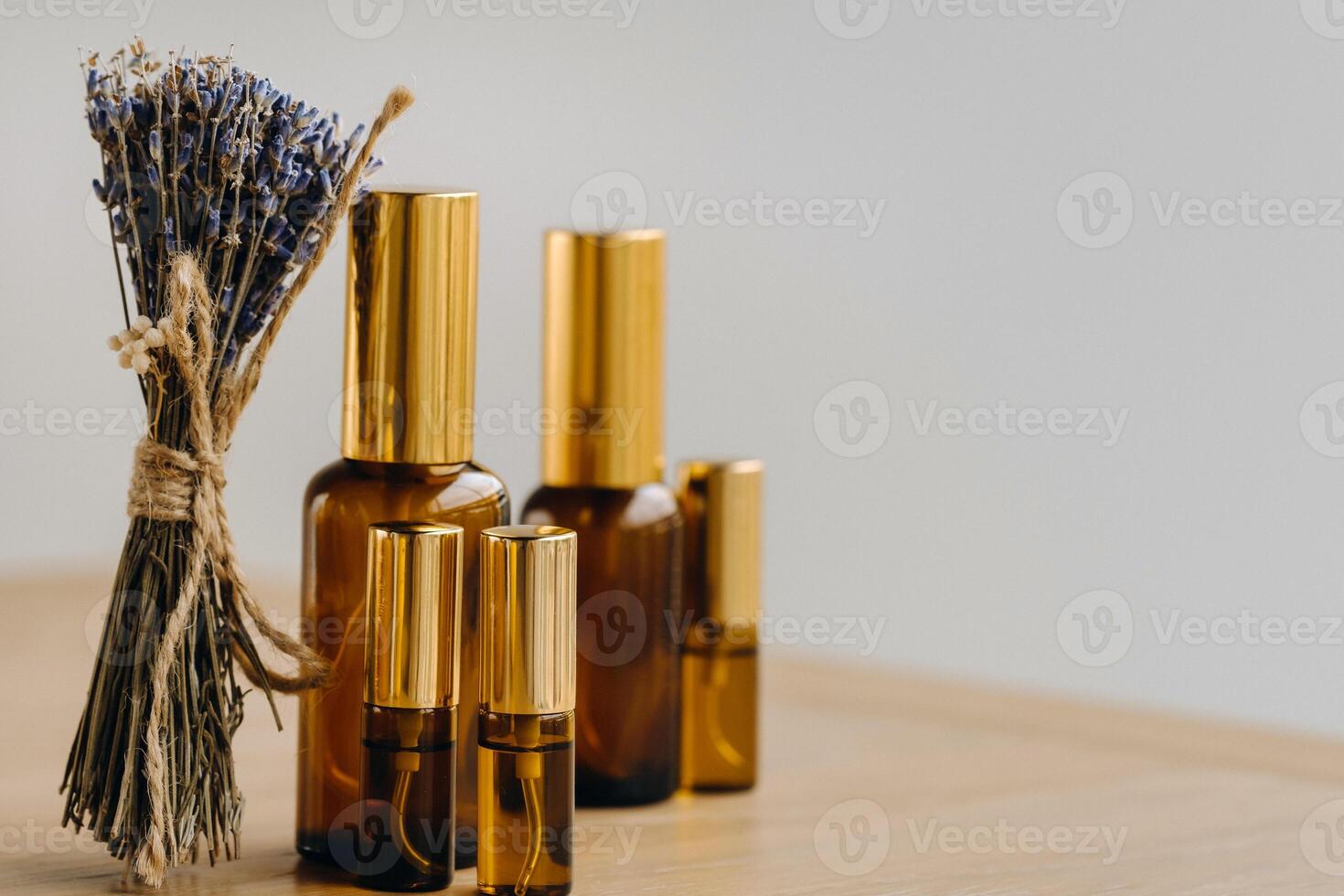 Essential oil in one bottle and dried lavender standing on the surface photo