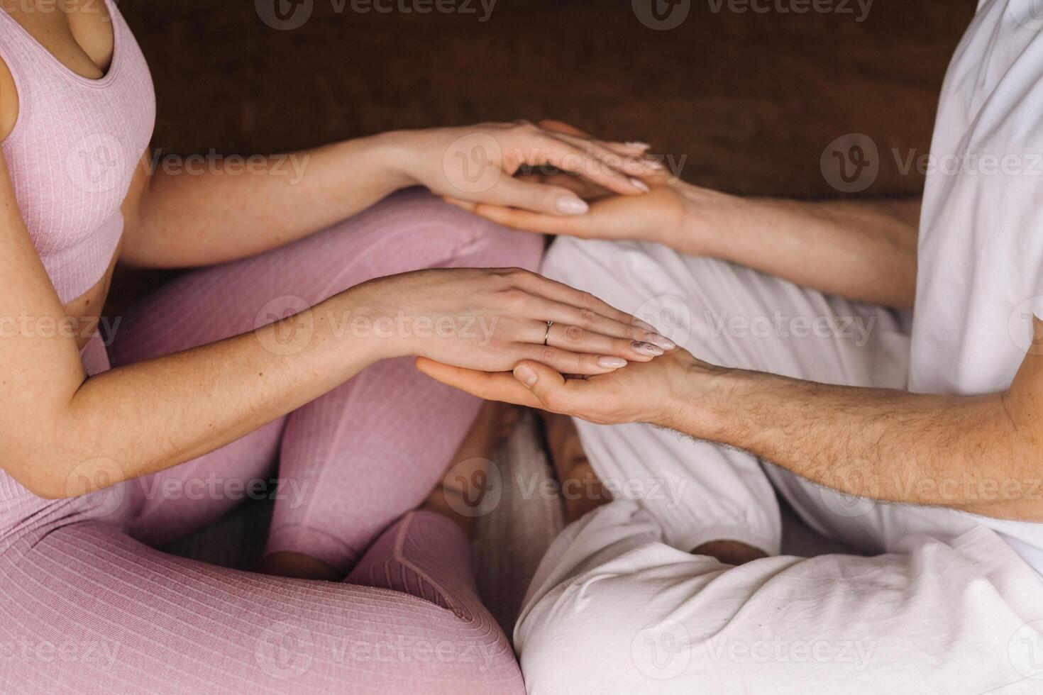 a woman and a man are engaged in pair meditation holding hands in the gym photo