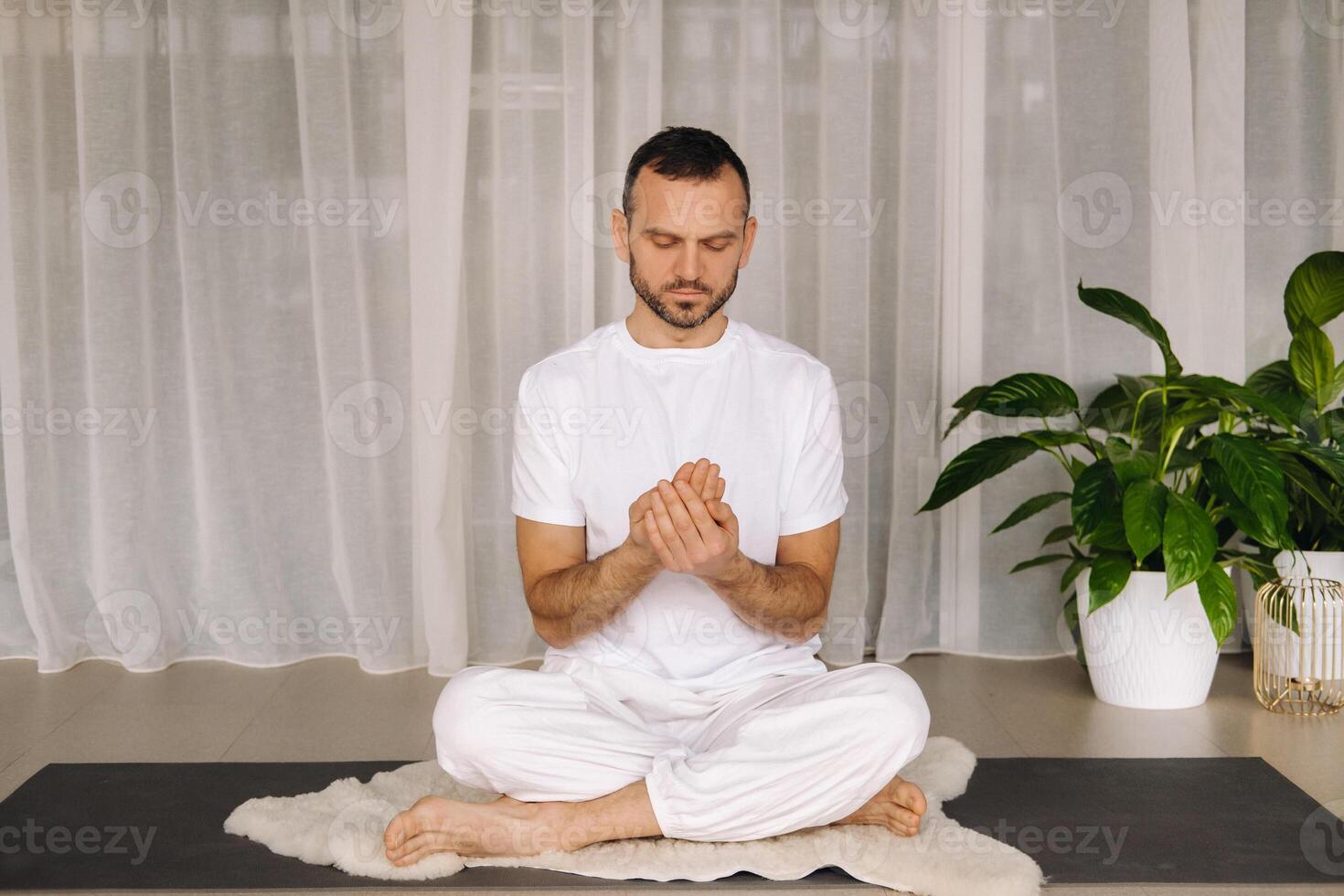 a man in white sportswear is doing yoga with a fitness room. the concept of a healthy lifestyle photo