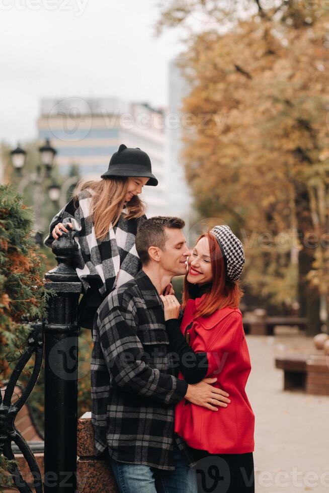 A stylish family of three strolls through the autumn city posing for a photographer . Dad, mom and daughter in the autumn city photo