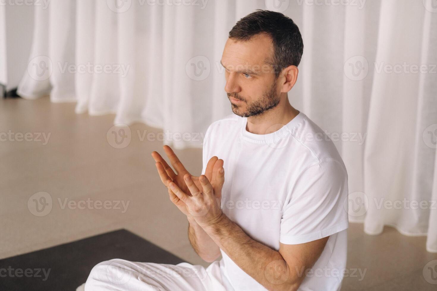 a man in white sportswear is doing yoga with a fitness room. the concept of a healthy lifestyle photo