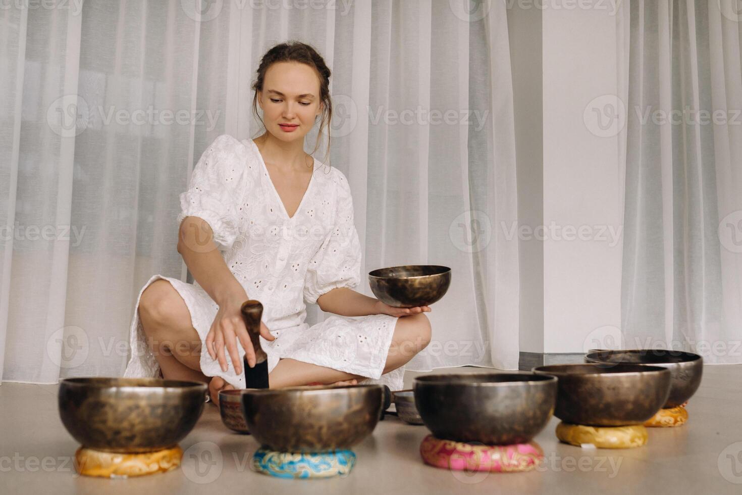 Portrait of a female yoga teacher playing a Tibetan bowl or singing a bell in the gym during a yoga retreat photo