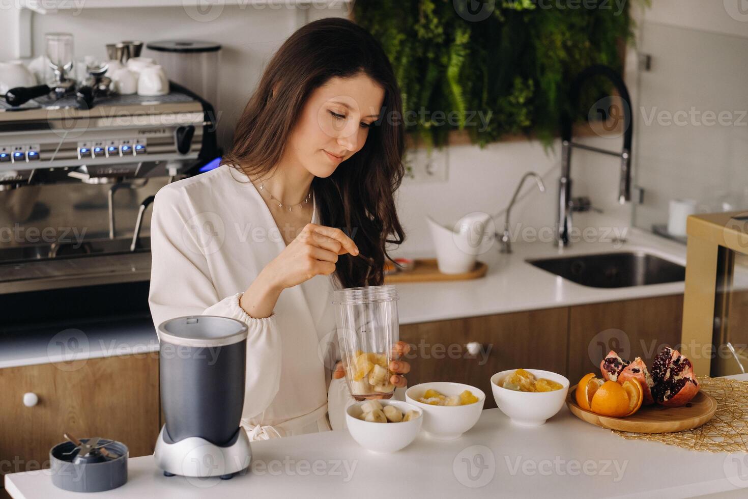 a girl makes a detox cocktail of fruit in the kitchen . Diet for weight loss photo