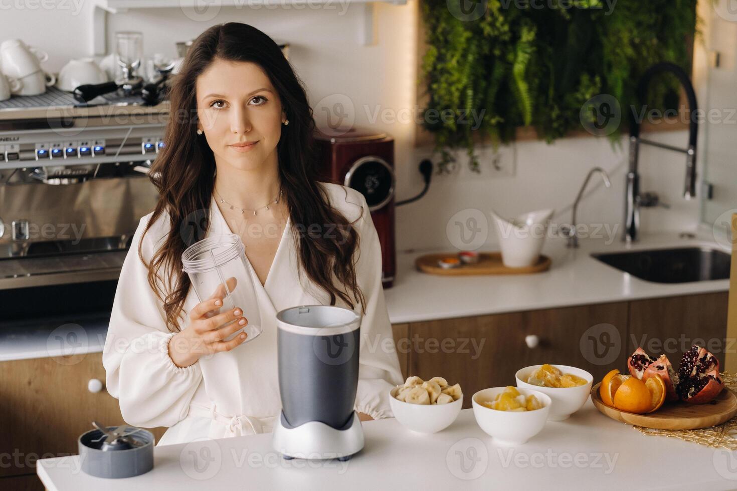 a girl makes a detox cocktail of fruit in the kitchen . Diet for weight loss photo