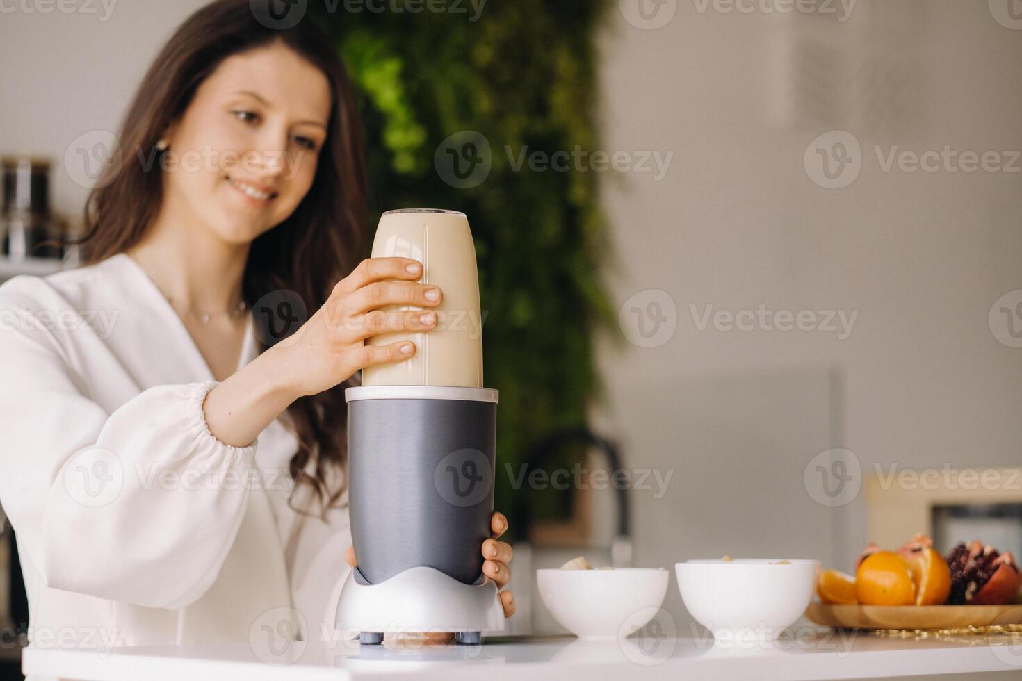 a girl makes a cocktail in a fruit blender in the kitchen. Diet for weight loss photo