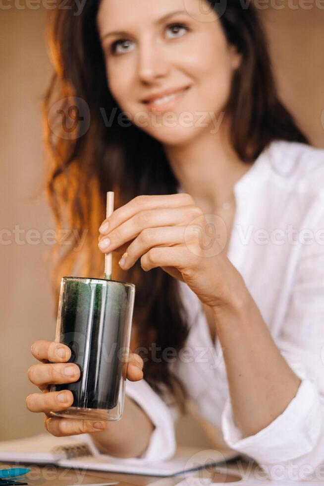 A young freelance woman with a cocktail in her hands at her workplace at work photo