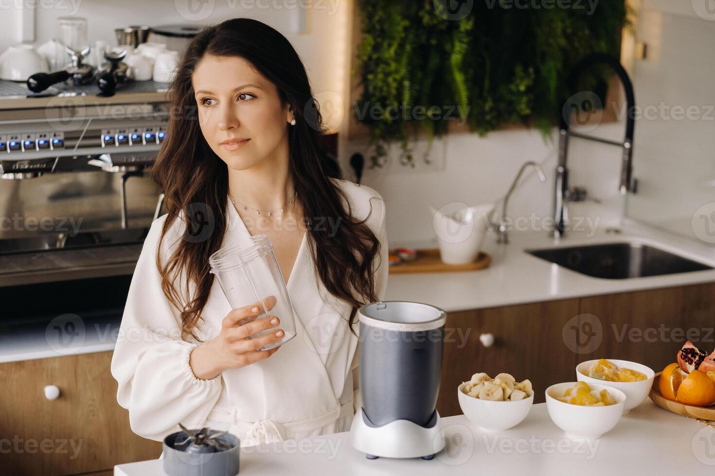 a girl makes a detox cocktail of fruit in the kitchen . Diet for weight loss photo