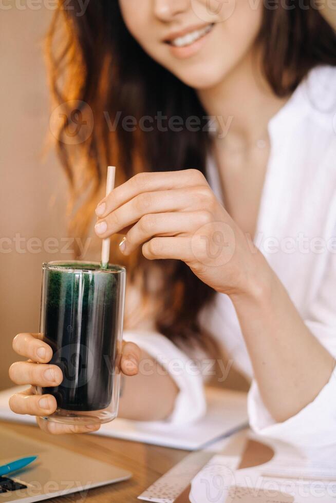 A young freelance woman with a cocktail in her hands at her workplace at work photo
