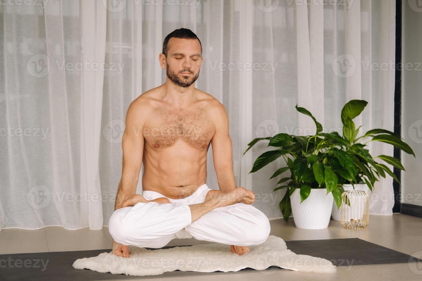 a man with a bare torso does yoga in a fitness room. the concept of a healthy lifestyle photo