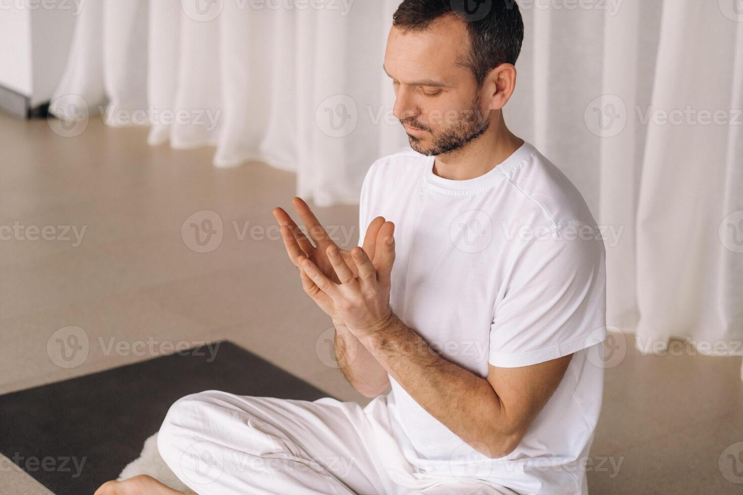 un hombre en blanco ropa de deporte es haciendo yoga con un aptitud habitación. el concepto de un sano estilo de vida foto