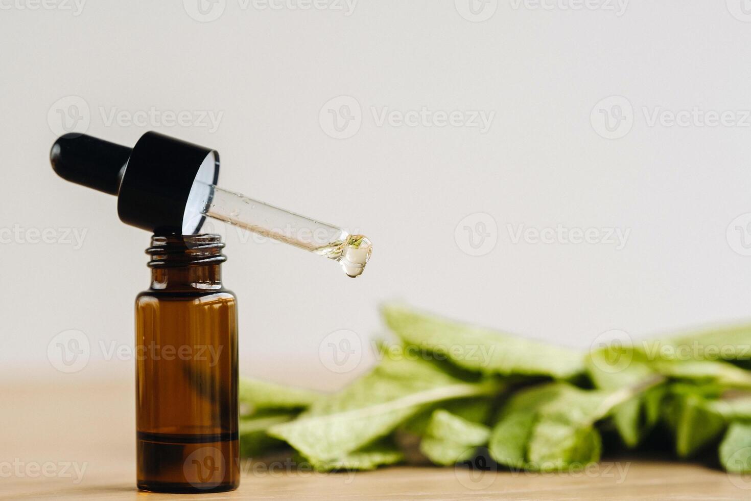 Essential oil in one bottle and mint plants lying on the surface photo